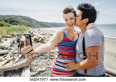 Pregnant lesbian couple posing for cell phone selfie on beach View Large Photo Image Stock Photo - Pregnant lesbian couple posing for cell phone selfie on beach. Fotosearch