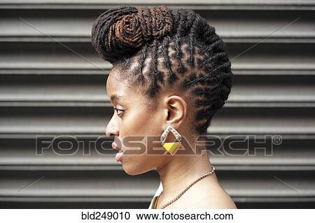Stock Image - Profile of African American woman with braids near metal wall. Fotosearch