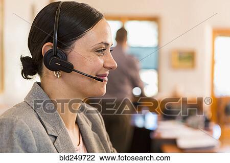 Stock Image - Profile of smiling Caucasian businesswoman wearing headset. Fotosearch