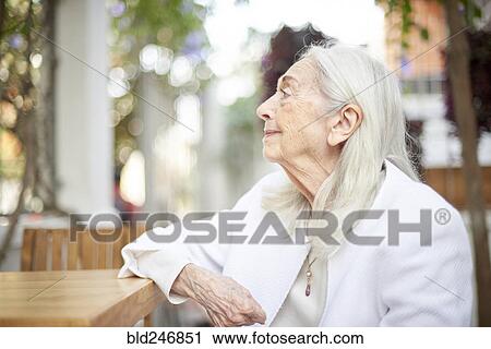Stock Image - Profile of smiling older Caucasian woman sitting at table. Fotosearch