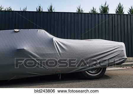 Protective cover on car near fence View Large Photo Image Stock Photograph - Protective cover on car near fence. Fotosearch