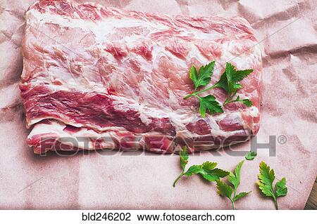 Stock Image - Raw meat and garnish on butcher paper. Fotosearch