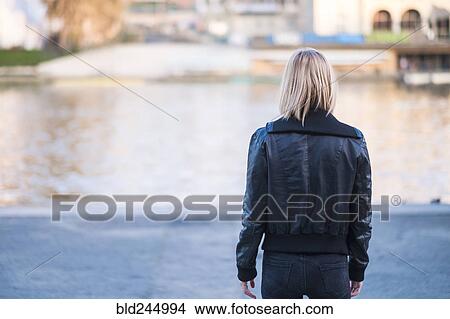 Picture - Rear view of Caucasian woman standing near river. Fotosearch