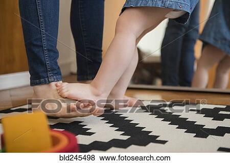 Stock Photo - Reflection in mirror of barefoot Caucasian mother and daughter. Fotosearch