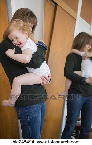Picture - Reflection in mirror of Caucasian mother holding daughter. Fotosearch