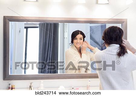 Picture - Reflection of Caucasian woman in bathroom mirror. Fotosearch