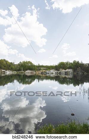 Stock Photograph - Reflection of clouds in still lake. Fotosearch