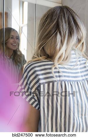 Stock Image - Reflection of smiling Caucasian woman in mirror. Fotosearch