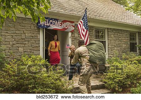 Stock Image - Returning African American soldier greeting son. Fotosearch