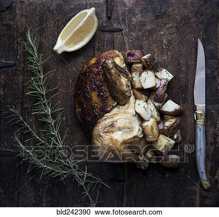 Stock Image - Roasted chicken with potatoes and lemon. Fotosearch