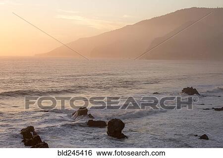 Rocks in ocean waves at sunset View Large Photo Image Stock Photograph - Rocks in ocean waves at sunset. Fotosearch