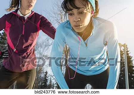 Stock Photograph - Runners listening to earbuds and resting. Fotosearch