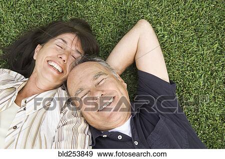 Senior couple laying in grass View Large Photo Image Stock Photo - Senior couple laying in grass. Fotosearch