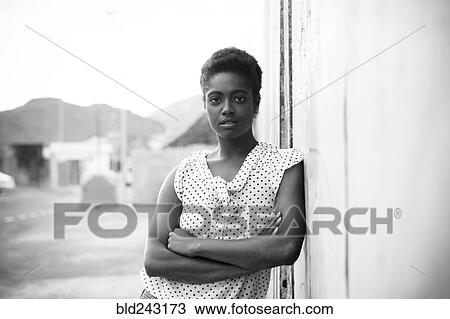Stock Image - Serious African American woman leaning on wall. Fotosearch