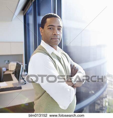 Stock Image - Serious Black businessman standing in office. Fotosearch