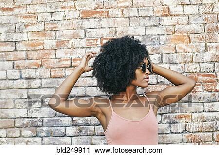 Stock Image - Serious Black woman near brick wall. Fotosearch