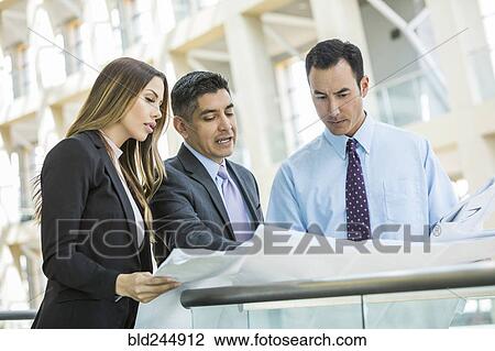 Serious business people reading blueprint in lobby View Large Photo Image Stock Image - Serious business people reading blueprint in lobby. Fotosearch