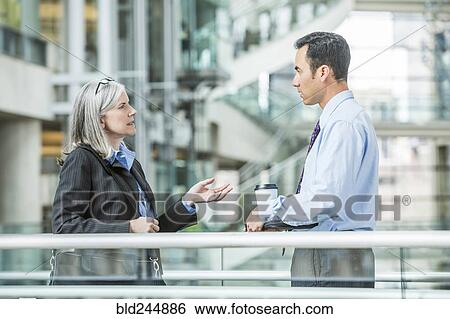 Stock Photograph - Serious business people talking in lobby. Fotosearch