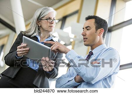 Stock Image - Serious business people using digital tablet. Fotosearch