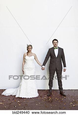 Stock Image - Serious Caucasian bride and groom holding hands. Fotosearch