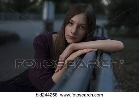 Stock Photo - Serious Caucasian woman leaning on bench. Fotosearch