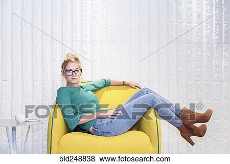 Serious Caucasian woman sitting in yellow chair View Large Photo Image Stock Photo - Serious Caucasian woman sitting in yellow chair. Fotosearch
