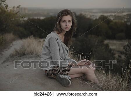 Serious Caucasian woman sitting on hill View Large Photo Image Stock Image - Serious Caucasian woman sitting on hill. Fotosearch
