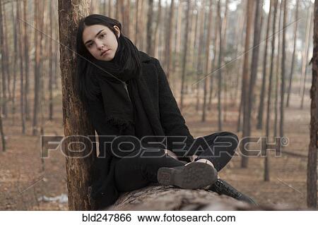 Serious Caucasian woman sitting on log in forest View Large Photo Image Stock Photograph - Serious Caucasian woman sitting on log in forest. Fotosearch
