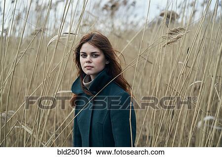 Picture - Serious Caucasian woman standing in field. Fotosearch