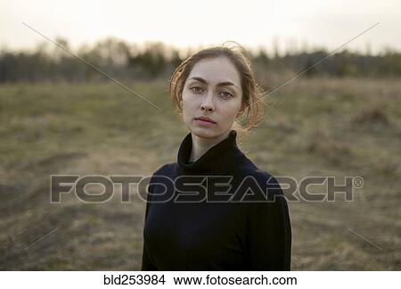 Picture - Serious Caucasian woman standing in field. Fotosearch