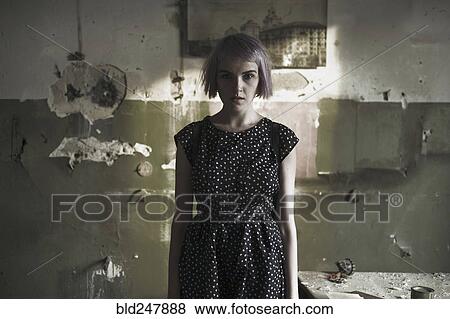 Stock Photo - Serious Caucasian woman standing near dilapidated wall. Fotosearch