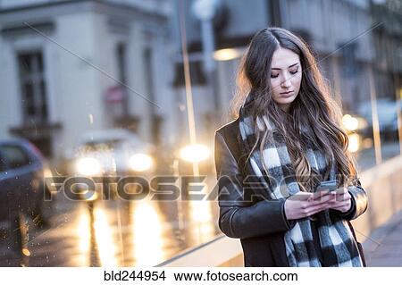 Picture - Serious Caucasian woman texting on cell phone outdoors. Fotosearch