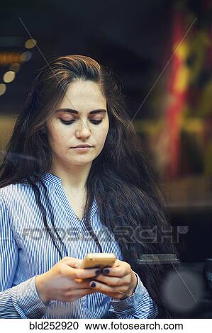 Stock Image - Serious Caucasian woman texting on cell phone. Fotosearch