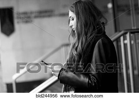 Stock Photograph - Serious Caucasian woman texting on cell phone. Fotosearch