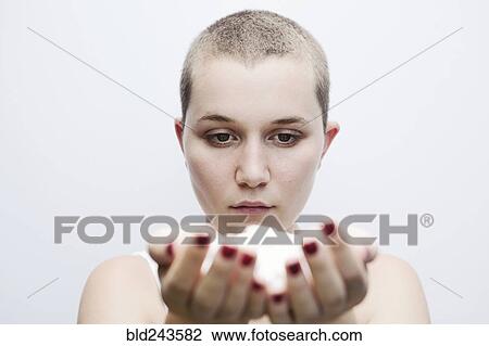 Stock Image - Serious Caucasian woman with shaved-head holding pills. Fotosearch