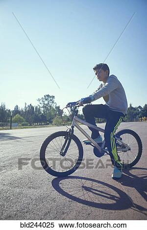 Stock Photography - Serious Hispanic boy on bicycle. Fotosearch