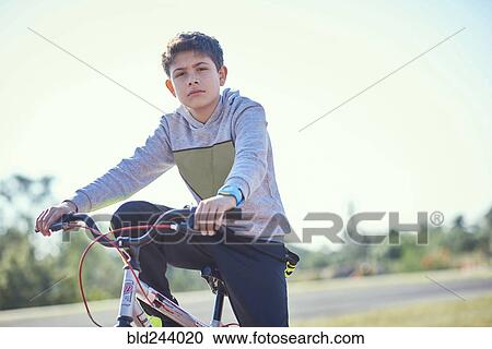 Stock Image - Serious Hispanic boy posing on bicycle. Fotosearch