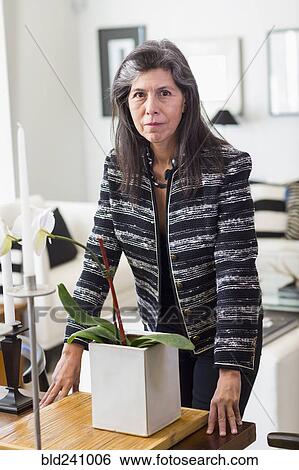 Serious Hispanic woman leaning over orchid View Large Photo Image Stock Photograph - Serious Hispanic woman leaning over orchid. Fotosearch