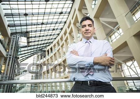 Stock Image - Serious Mixed Race businessman posing in lobby. Fotosearch