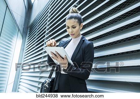 Serious Mixed Race businesswoman using digital tablet in corridor View Large Photo Image Stock Photo - Serious Mixed Race businesswoman using digital tablet in corridor. Fotosearch