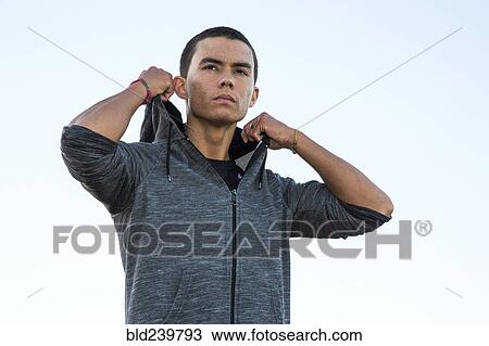 Stock Image - Serious Mixed Race man adjusting hoody. Fotosearch