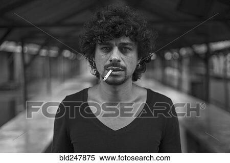 Stock Photography - Serious Mixed Race man smoking cigarettes. Fotosearch