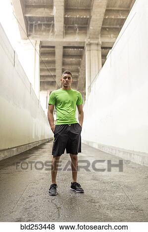Stock Photo - Serious Mixed Race man standing under bridge. Fotosearch