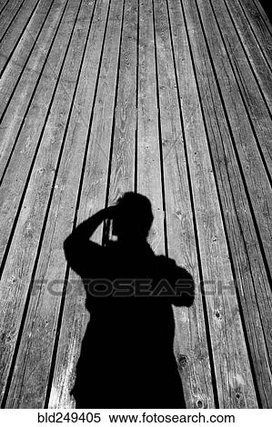 Stock Photography - Shadow of Caucasian man with camera on wooden floor. Fotosearch