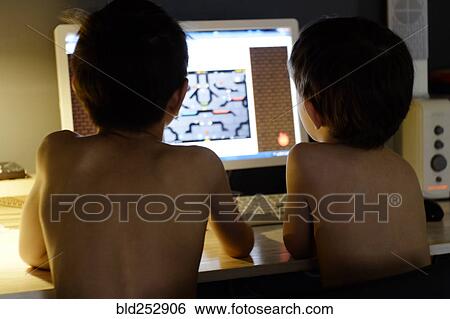 Stock Photograph - Shirtless Caucasian boys playing video game on computer. Fotosearch