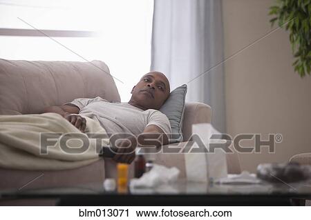 Stock Image - Sick Black man laying on sofa. Fotosearch