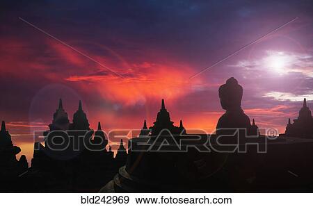 Stock Photo - "Silhouette of statue of Buddha at sunset, Borobudur, Java, Indonesia". Fotosearch