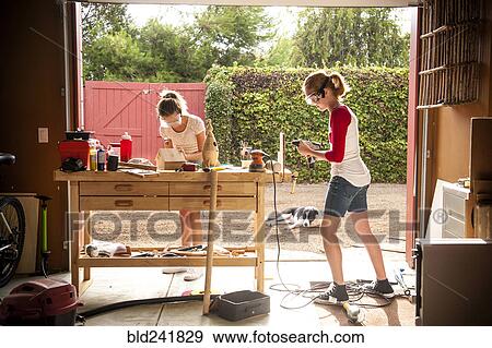 Stock Photo - Sisters building birdhouse in garage. Fotosearch