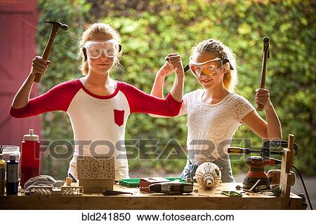 Sisters flexing muscles and holding hammers View Large Photo Image Stock Image - Sisters flexing muscles and holding hammers. Fotosearch