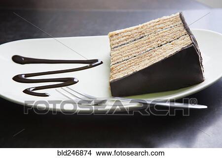 Picture - Slice of cake on plate with fork and chocolate syrup. Fotosearch